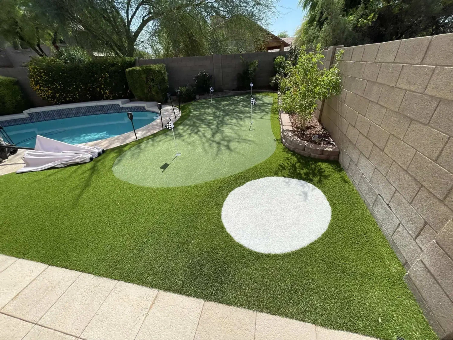 backyard putting green in Tucson AZ installed by Sonoran Turfscapes. Features 4 holes and a small sand trap next to the pool